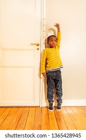 Boy Measuring His Height Benchmark On Door At Home