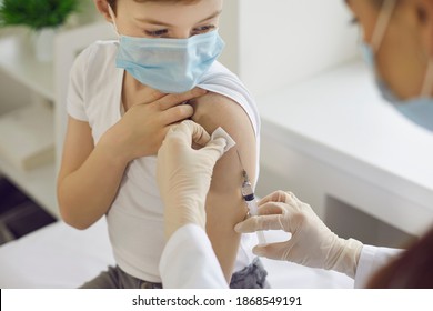 Boy In Medical Face Mask Getting Flu Shot At Doctor's Office. Cropped Nurse Giving Child Intramuscular Antivirus Injection. Vaccination For Children, Healthcare, And World Immunization Week Concept