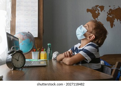 Boy In Medical Mask During On Line Distant Lesson, Not Paying Attention To What Teacher Is Saying. Student Is Not Involved Into Studying Process.