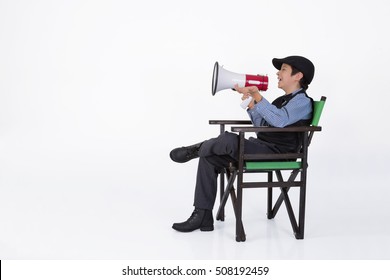 Boy With Megaphone On Chair Filmmaker, Smiling And Giving Directions, On White Background.