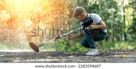 a boy with a metal detector in the park. High quality photo