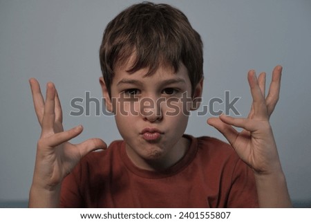 Boy mimicking an animal with hands, puckered lips for effect. Captures a child's imaginative play and their connection with nature