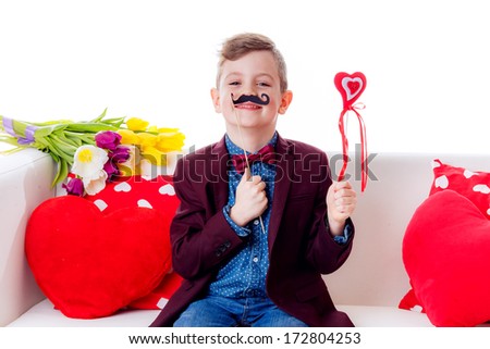 boy with a mustache and a heart in his hands, sitting on the couch, April Fool's Day. valentine's day, March 8, International Women's Day, Mother's Day, April 1
