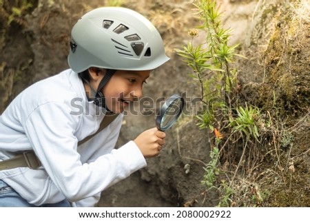 Boy observing a plant with a magnifying glass