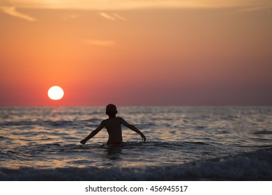 Boy in the Ocean at Sunset.