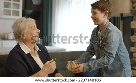 Boy offering candy in bowl to his elderly grandmother. Little boy offering candy to his elderly grandmother to celebrate the traditional Eid al-Fitr (candy feast) after the end of Ramadan.