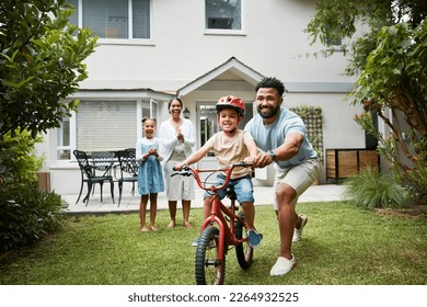 Boy on bicycle learning with proud dad and happy family in their home garden outdoors. Smiling father teaching fun skill, helping and supporting his excited young son to ride, cycle and pedal a bike - Powered by Shutterstock