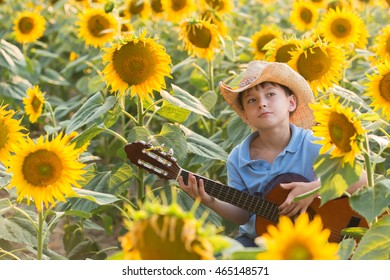 Boy on a field of sunflowers, small farmer playing guitar