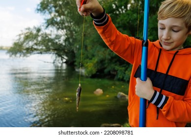 A Boy On A Fishing Trip Holds A Fishing Rod In Front Of Him And Cuts The Fish That He Caught