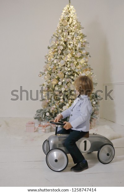 boy on the
retro toy car near the christmas
tree