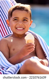 Boy On Summer Holiday On Lounger By Swimming Pool Eating Ice Cream