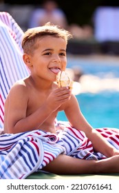 Boy On Summer Holiday On Lounger By Swimming Pool Eating Ice Cream