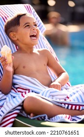 Boy On Summer Holiday On Lounger By Swimming Pool Eating Ice Cream