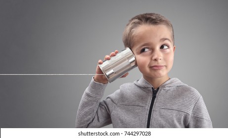 Boy on tin can phone listening to curious good news