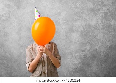 Boy with orange balloon on grey background