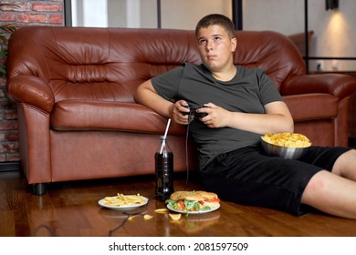 Boy Is Overeating. Fat Child, Food Addiction And Behavior Problems. Lazy Teenage Boy On Floor Eating Fast Food Alone After School, Lead Unhealthy Lifestyle. Overeating, Obesity, Overweight