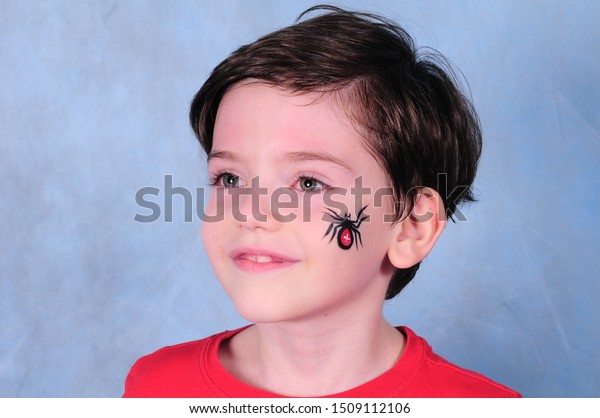 A boy with a\
painted face in the image of a spider in a Studio in Moscow on a\
blue background March 1, 2015