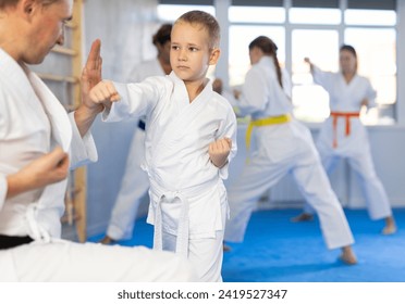 Boy is paired with man teacher to learn how to strike and rehearses blocking opponent, using karate technique - Powered by Shutterstock