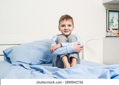 Boy In Pajamas Sitting On The Bed