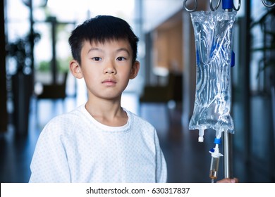 Boy patient holding intravenous iv drip stand in corridor at hospital - Powered by Shutterstock