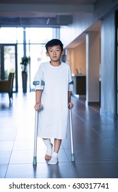 Boy patient walking with crutches in corridor at hospital