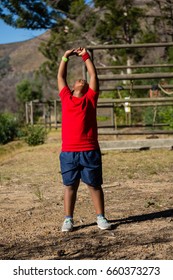 Boy performing stretching exercise during obstacle course training in the boot camp