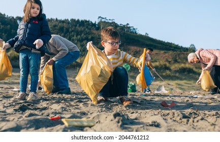 Junge, der Müll mit einer Gruppe Freiwilliger am Strand aufsammelt