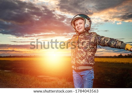 A boy in a pilot's helmet on a sunset background. Dream concept, choice of profession, game. Copy space