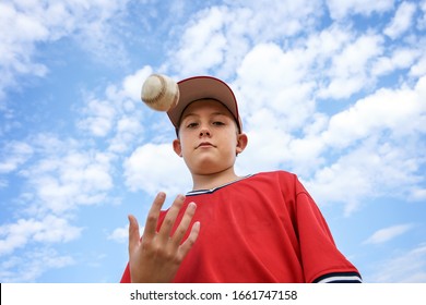 Boy pitcher tossing a baseball in the air, ready to pitch, motion blur on hand and ball