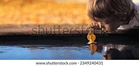 boy play with autumn leaf ship in water, children in park play with boat in river