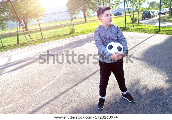A\
boy in play with a ball, safe playground away from\
cars