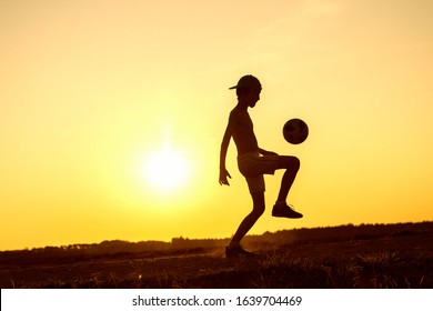 Boy playing with ball in nature in hot evening, silhouette of playing child at sunset in countryside - Powered by Shutterstock