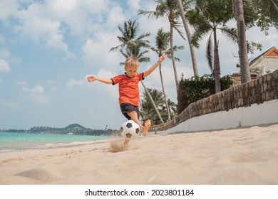 Boy Playing Barefoot Soccer On The Beach With A Black And White Ball On An Island By The Sea