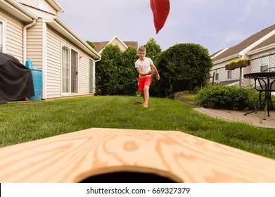 Boy playing bean bag toss in the backyard! 
