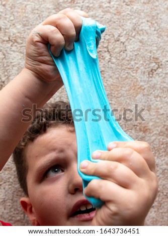 The boy is playing with a blue slime in his hands.