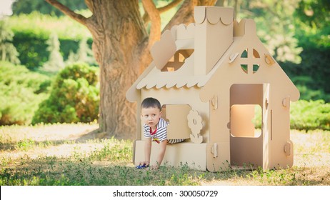 boy playing in cardboard house in a city park