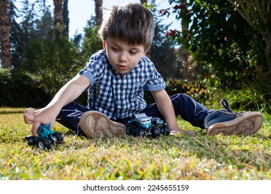 boy is playing the cars in the garden on the grass in the sunny day