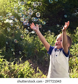 Boy Playing Catch Soap Bubbles Outdoors