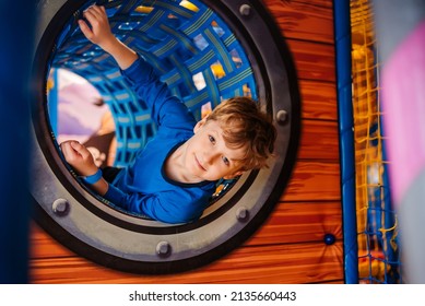 Boy is playing in children's playroom. Child crawls through game tunnel on playground.