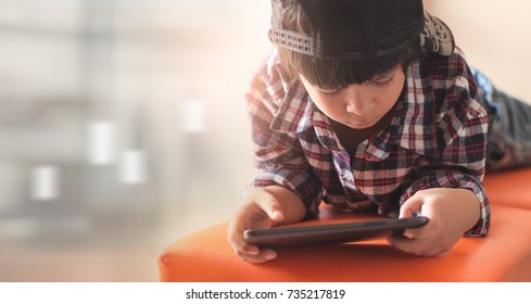 Boy playing digital tablet while lying on sofa at home 