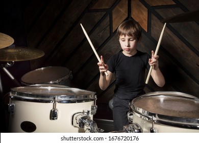 A Boy Is Playing With A Drumstick. The Child Behind The Drum Kit.