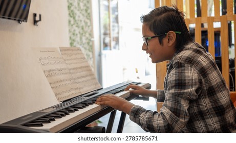 Boy playing electronic keyboard, practicing music while reading sheet music in a home setting