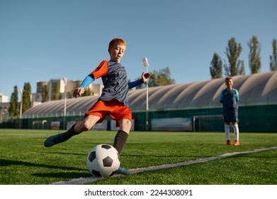 Boy playing football on field and kicking soccer ball - Powered by Shutterstock