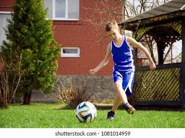 The Boy Is Playing Football In The Yard.The Boy Is Playing Football In The Courtyard Of The House.