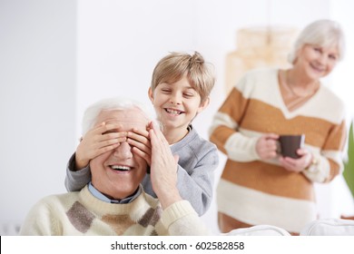 Boy playing with grandfather, covering his eyes