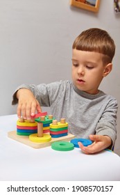 The boy is playing in his room. Learning shapes and colors. A child plays with a sorter. Educational logic toys for kid's. Montessori Games for Child Development.