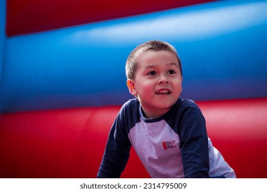 A boy playing at the inflatable trampoline theme park, playground, or playing field with one or more bouncy play areas and features during summer. - Powered by Shutterstock