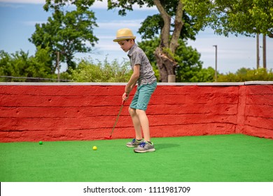 Boy Playing Mini Golf. Child With A Putter On Golf Course