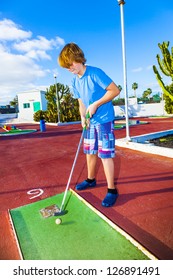 Boy Playing Mini Golf In The Course