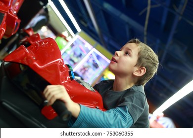 Boy playing in motorcycle simulator at indoor playground